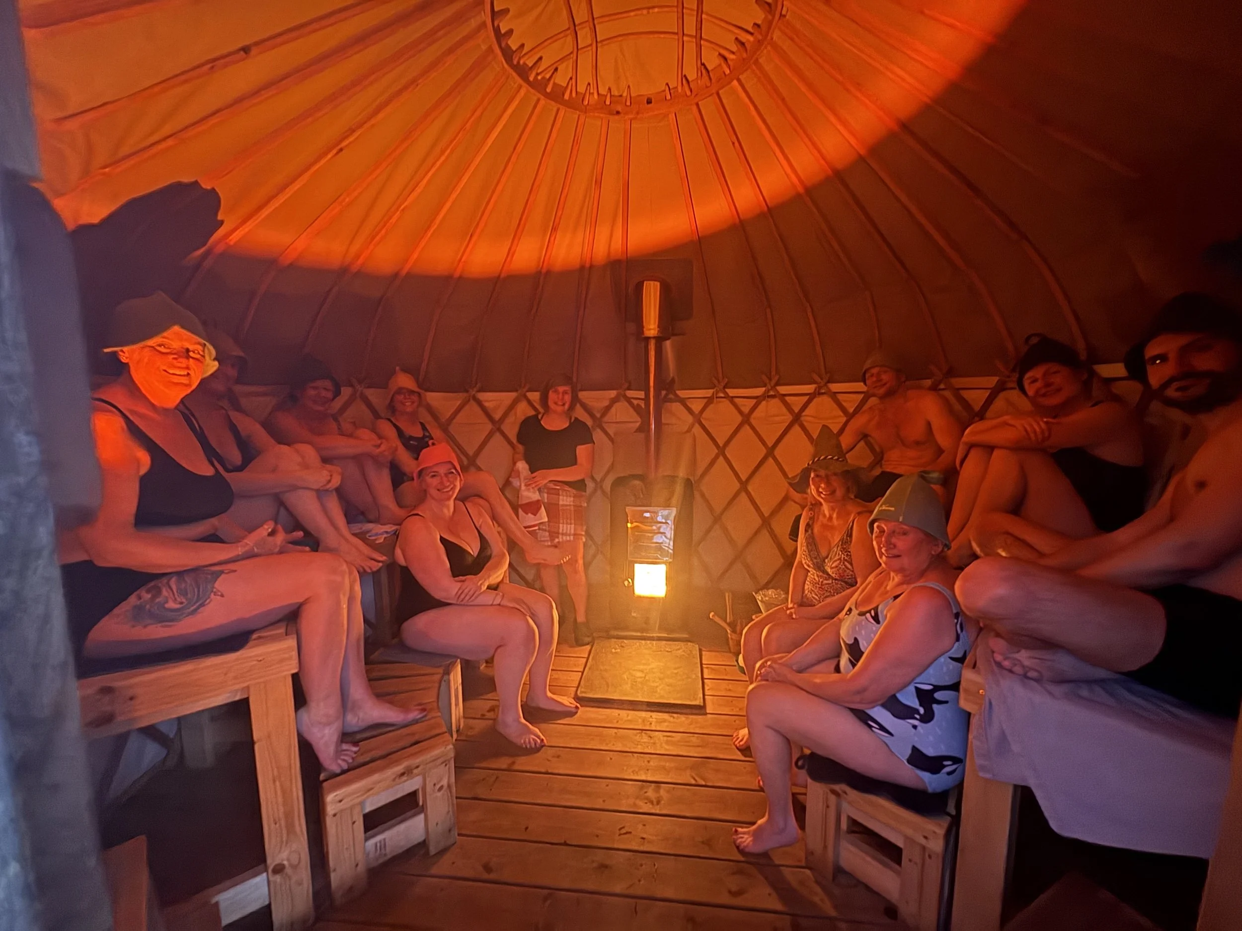 Gurts Yurt, our sauna yurt. A group of people sitting facing the camera during a sauna aufguss ritual in the only publicly available sauna yurt in the UK.