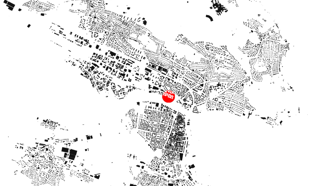 Stadtplan mit schwarzen Gebäuden und Straßen auf weißem Hintergrund, mittig ein rotes Symbol mit weißem Text.