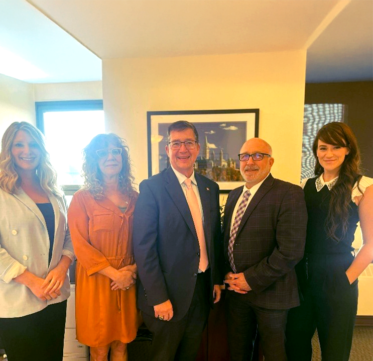 Five people standing together in an office.