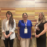 Three women standing in front of a wall smiling at the camera.