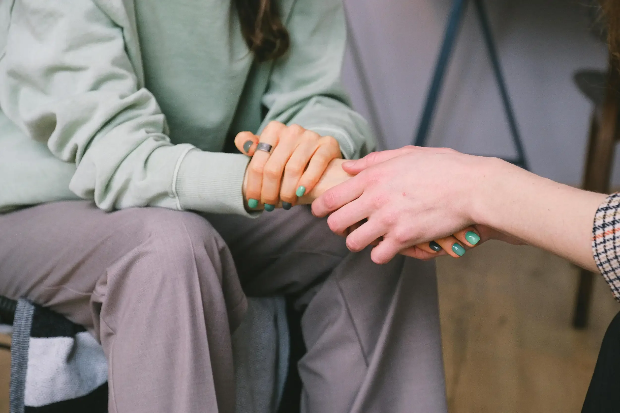 Two people holding hands, one person's hand gently grasping the other's.