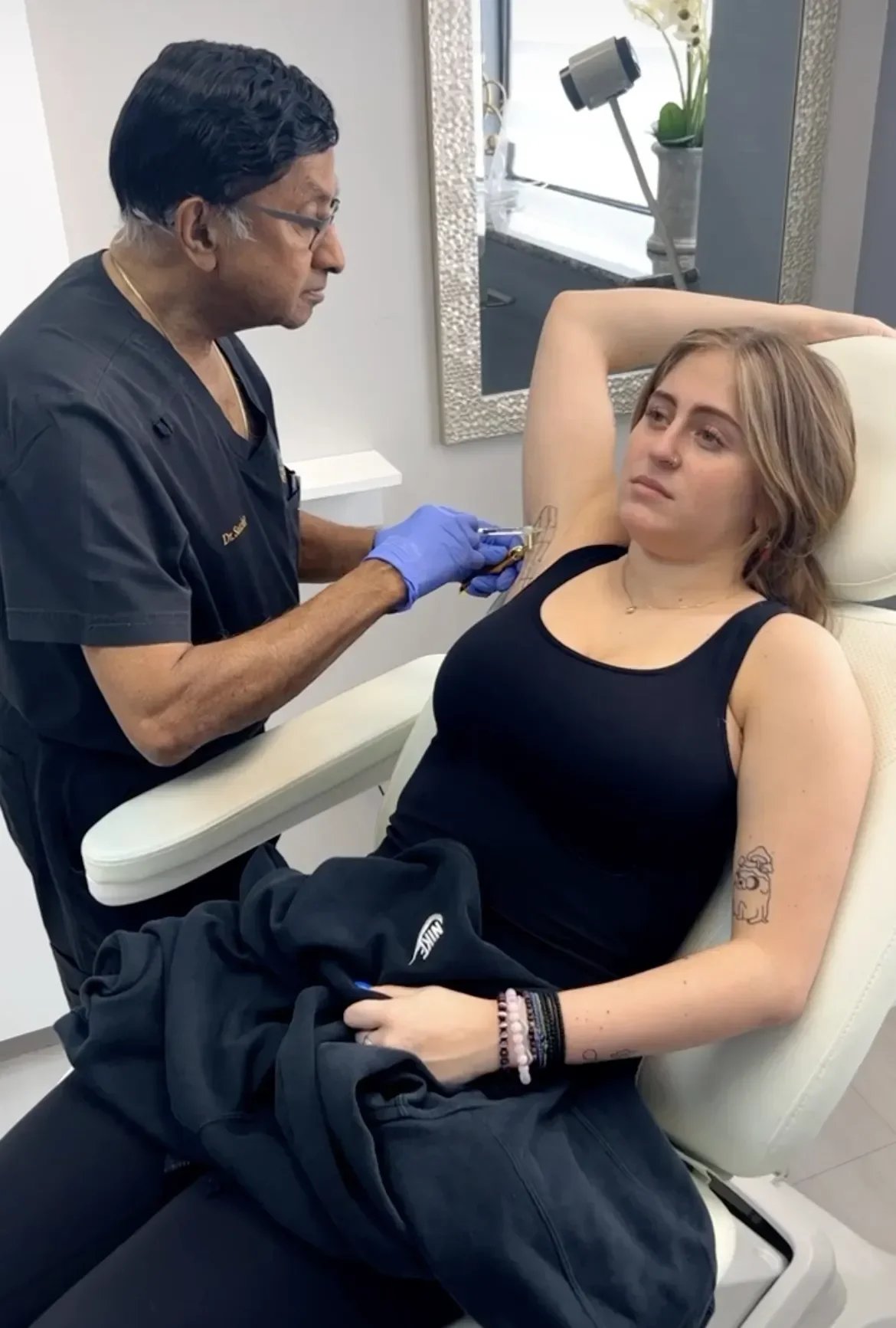 A woman is receiving a tattoo on her armpit from a tattoo artist in a studio.