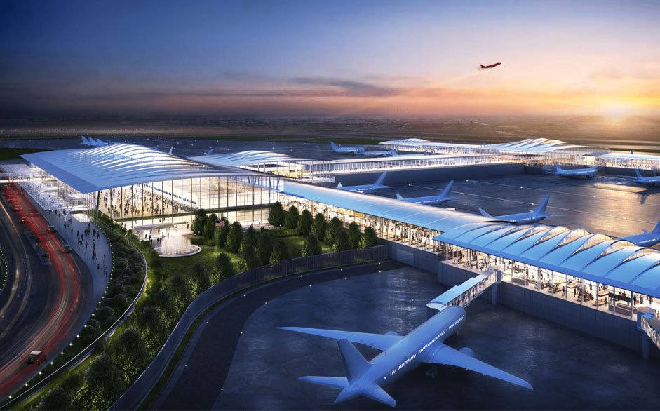 A modern airport terminal at sunset with multiple airplanes parked outside and an airplane taking off in the sky.