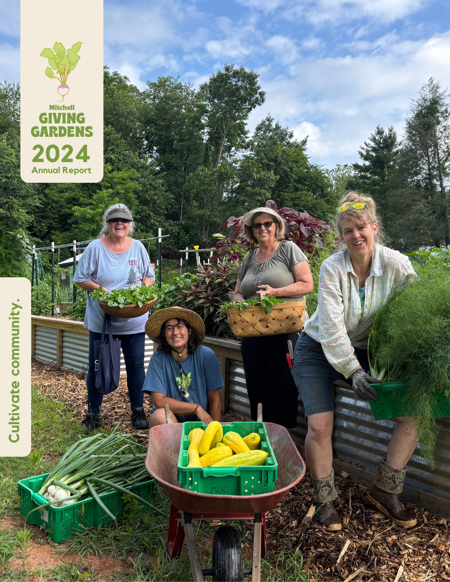 Four women and one young girl in a garden with raised beds and trees, holding baskets of harvested vegetables and smiling. There is a wheelbarrow with yellow zucchinis and a basket of green onions in front.