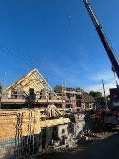 Construction site with a building under construction, crane in the sky, and blue sky background.