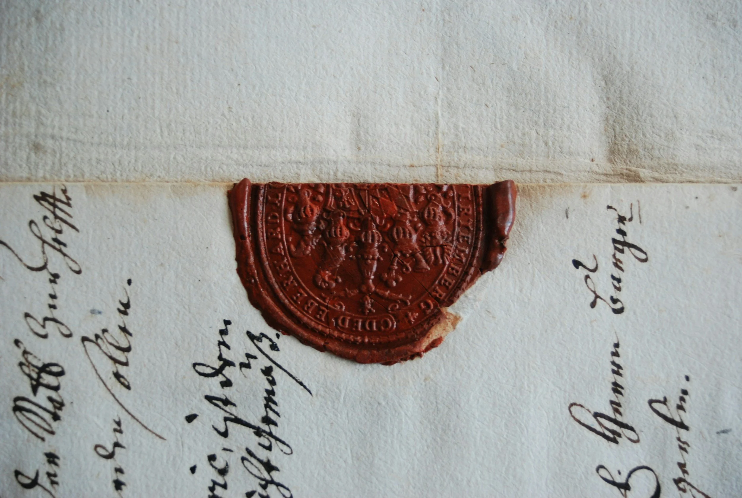 Close-up of a document with a red wax seal, containing colonial-era handwritten text.