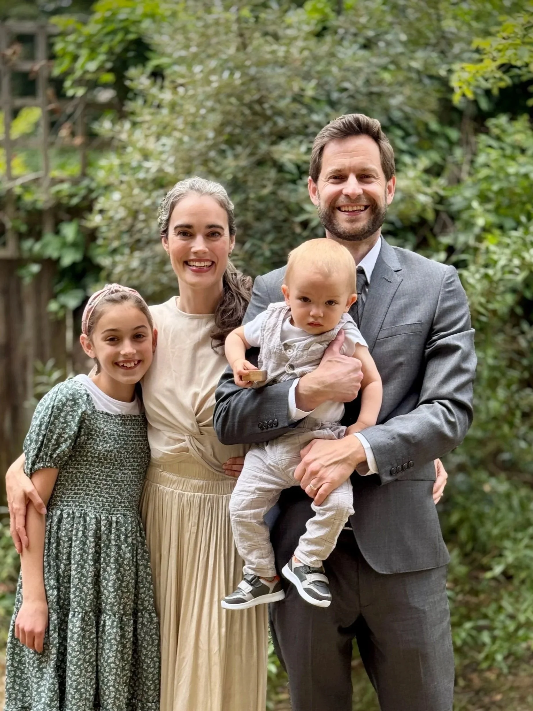 George the pastor standing with his happy family of four outdoors.