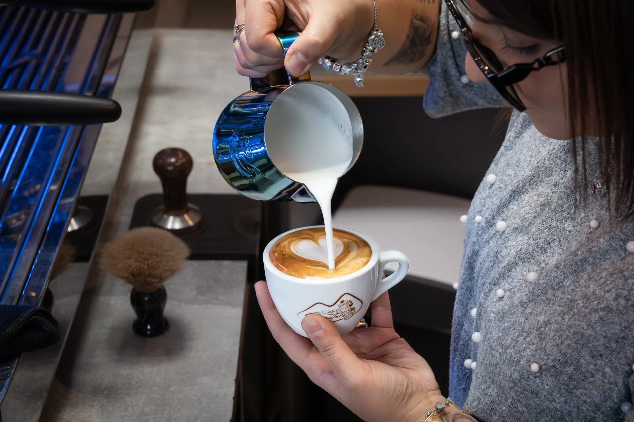 In dem Bild sieht man wie ein Cappuccino mit Latte-Art gemacht wird.