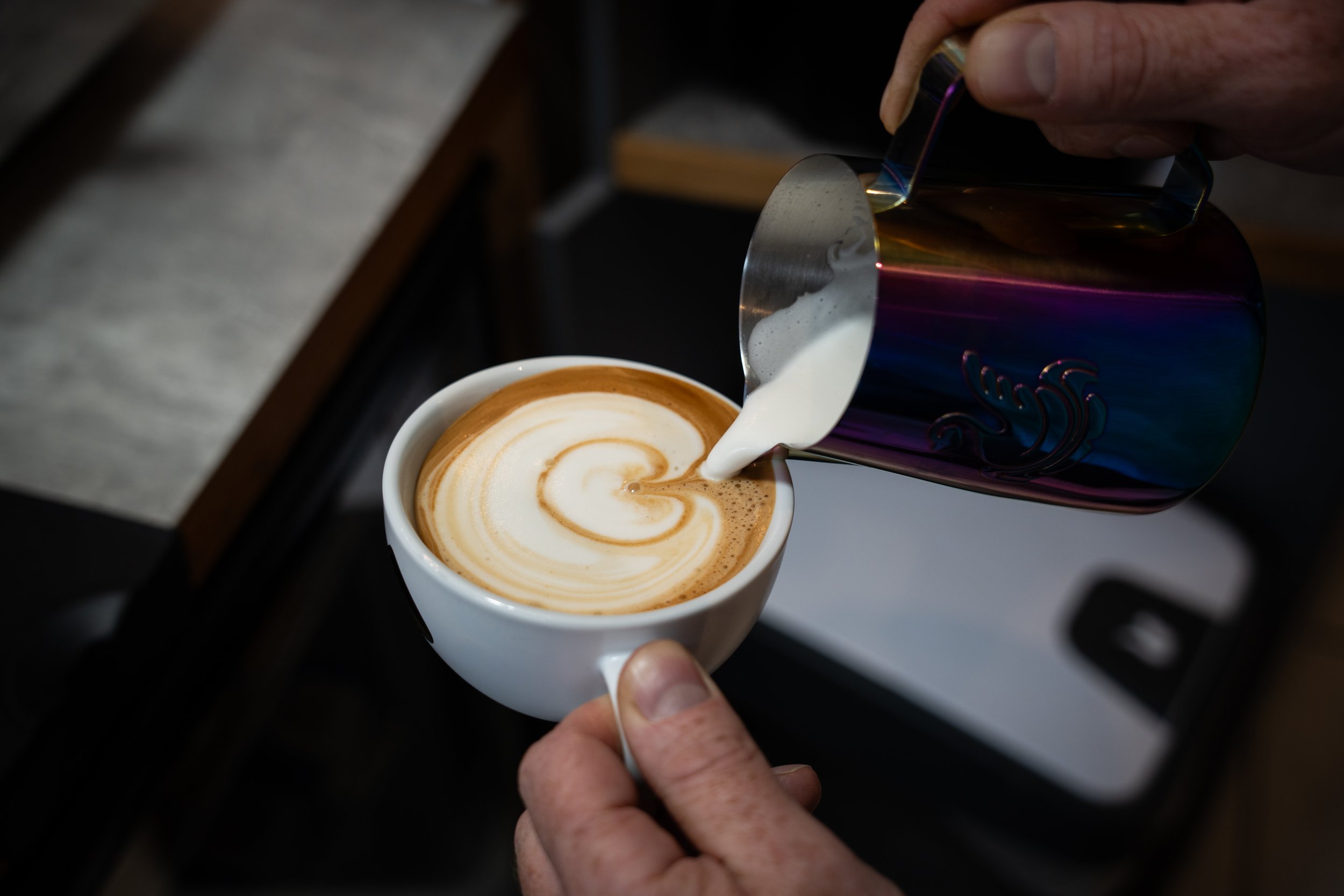 In diesem Bild wird aufgeschäumte Milch ausgegossen um einen Cappuccino in Latte-Art zu machen.