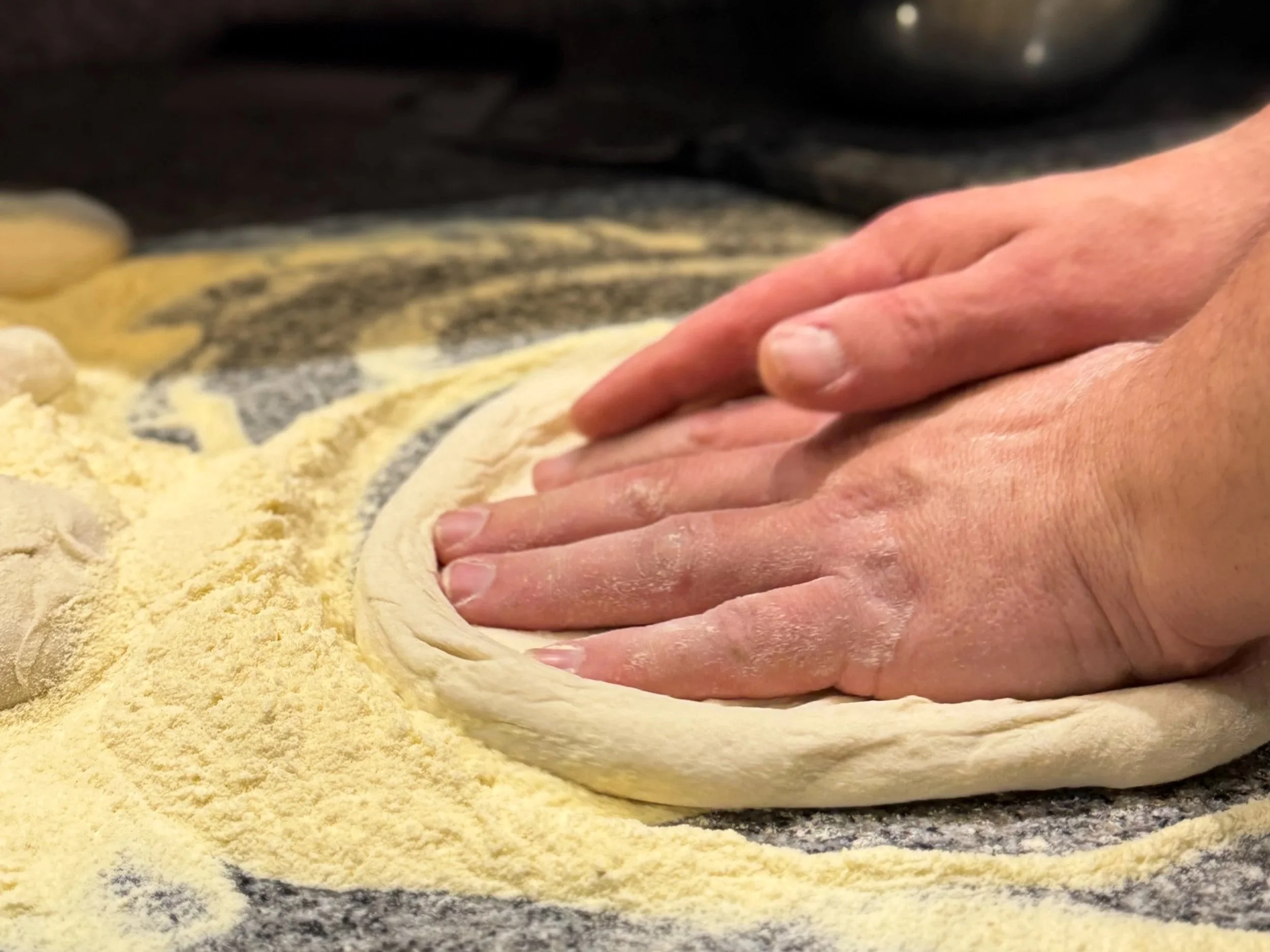 Close-up of a person kneading dough on a floured surface.
