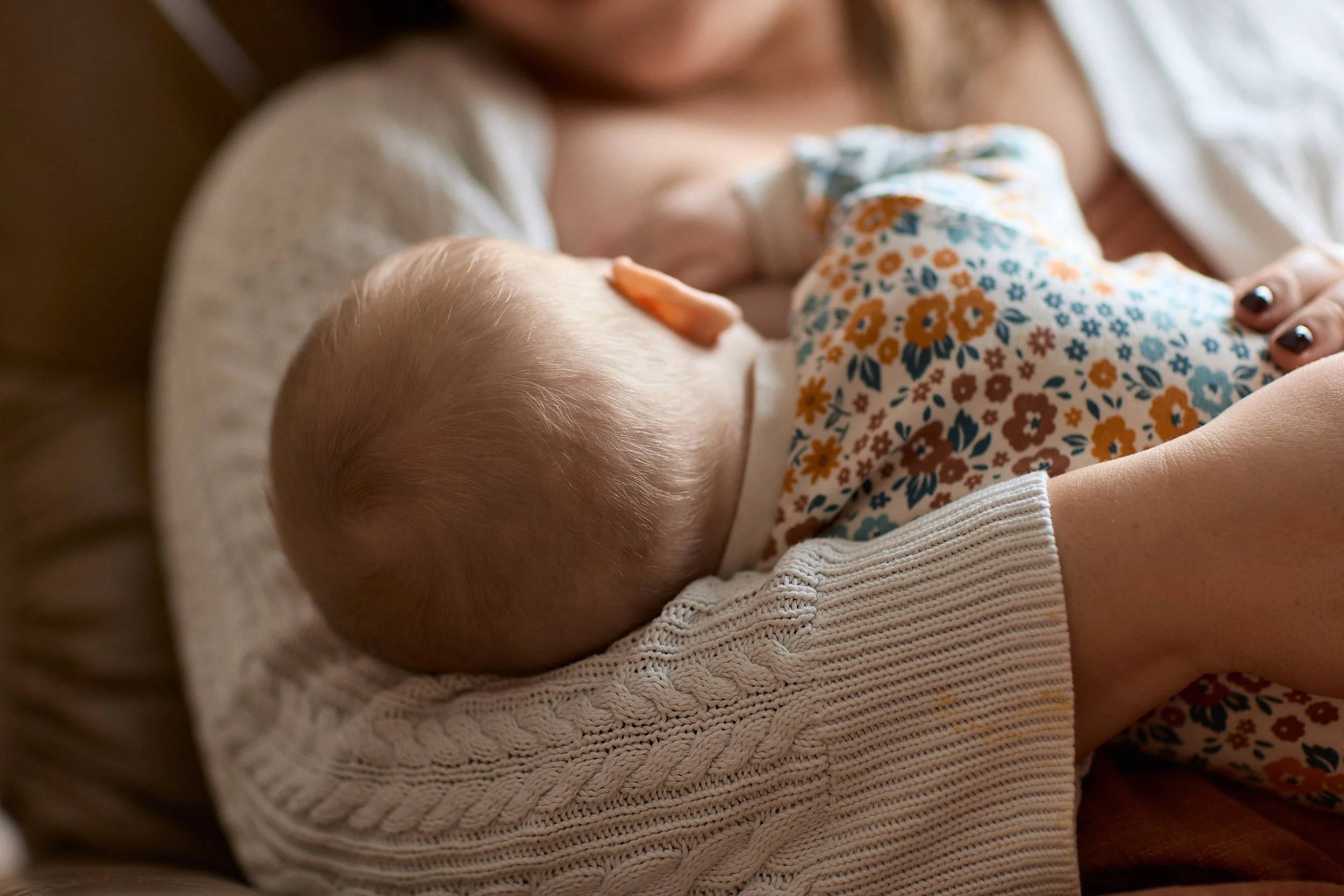 New mom latching and breastfeeding her baby without nipple pain after receiving breastfeeding help.