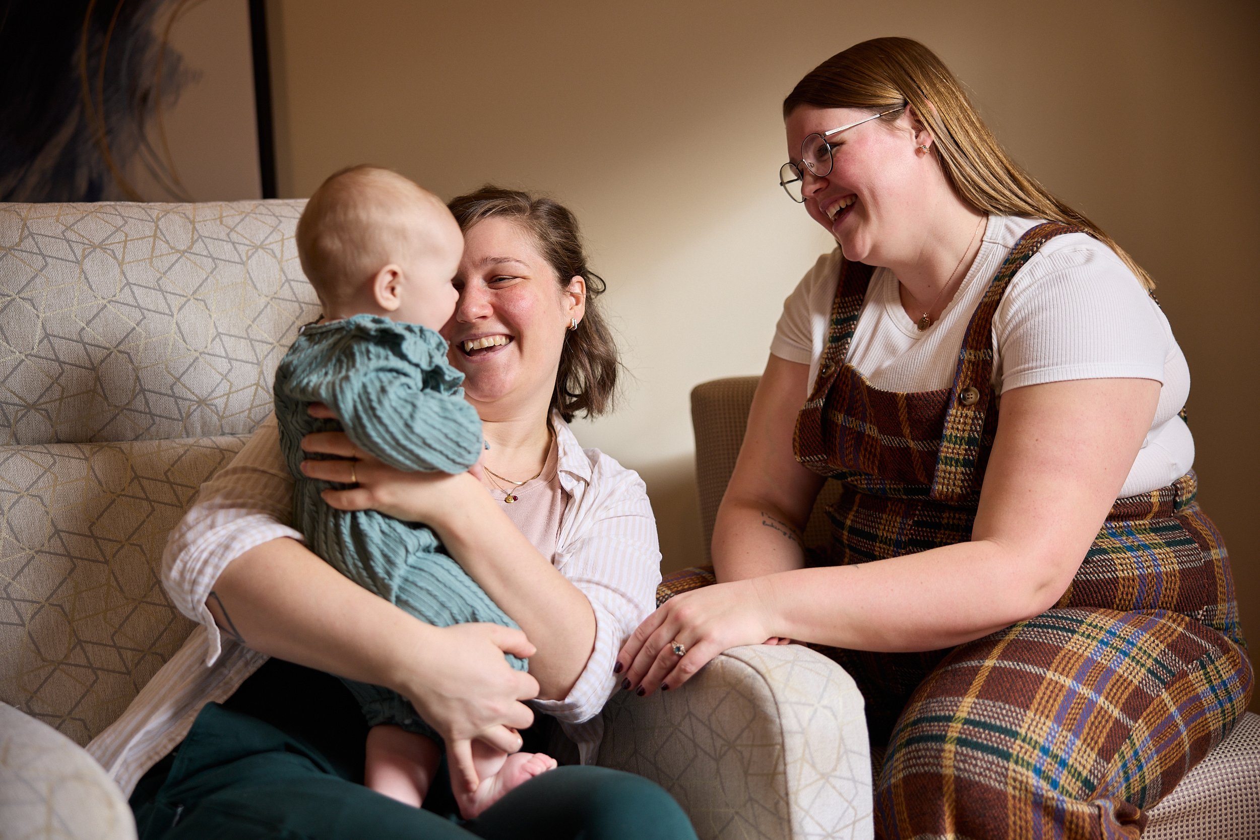 Lactation Consultant sitting in the home of a new mom and her tongue tied baby, smiling at baby.