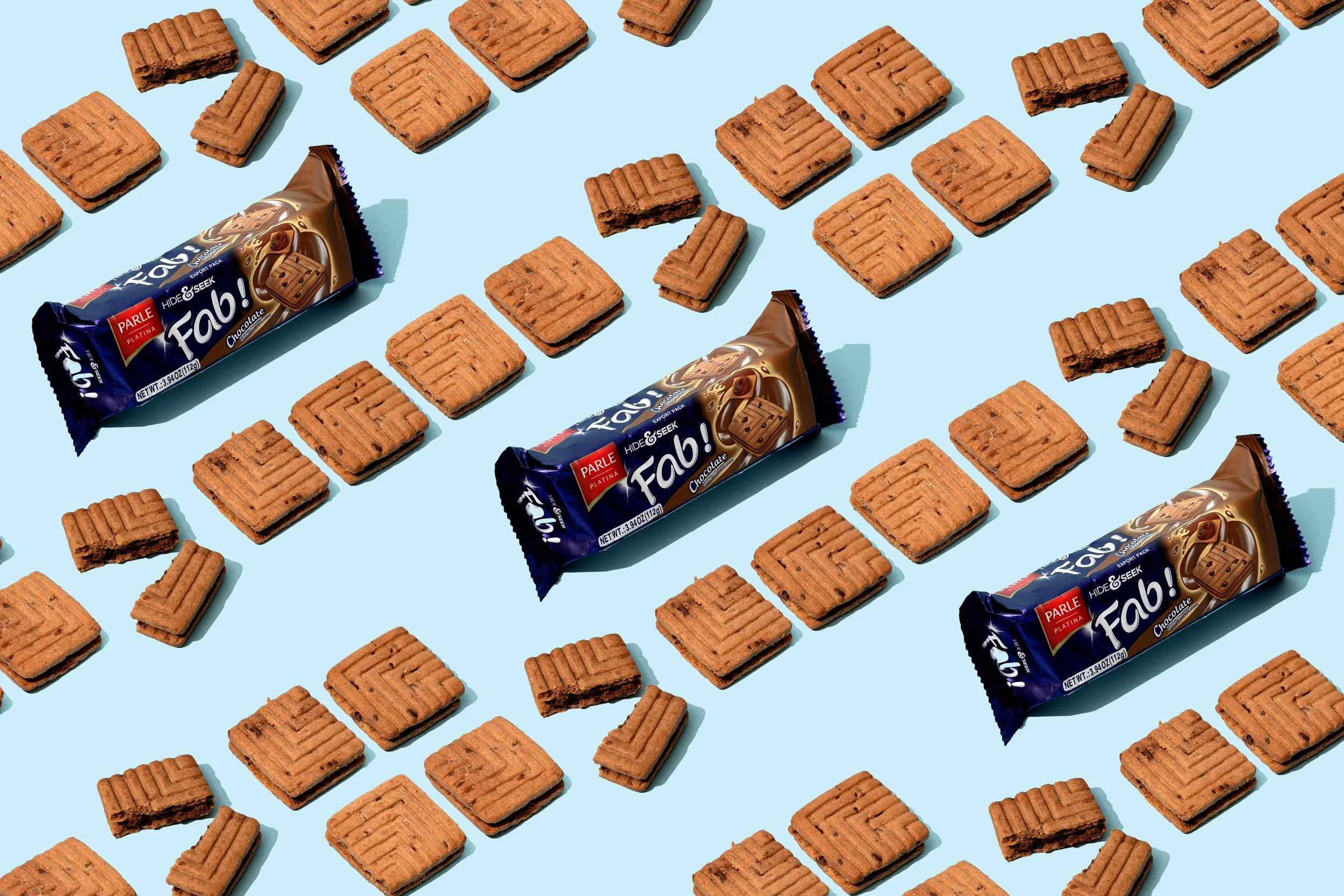 Multiple rectangular chocolate cookies and two chocolate wafer snack packs arranged on a light blue background.