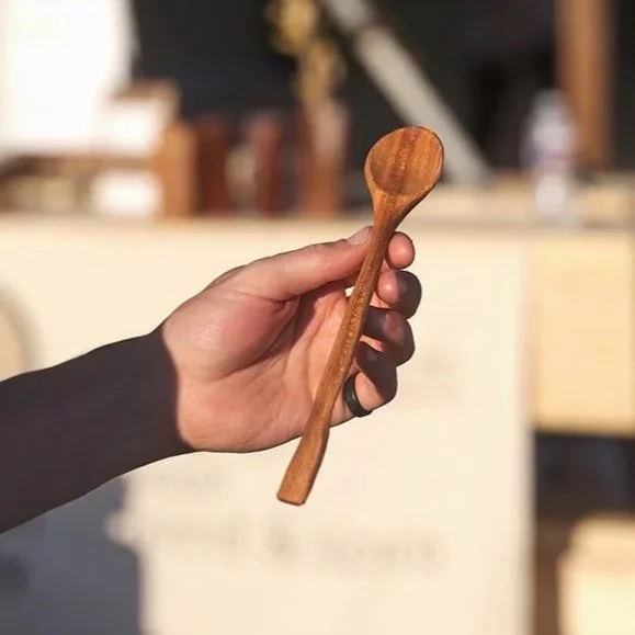 a photo of a hand holding an hand-carved wooden spoon at a spoon carving demo at war eagle craft show