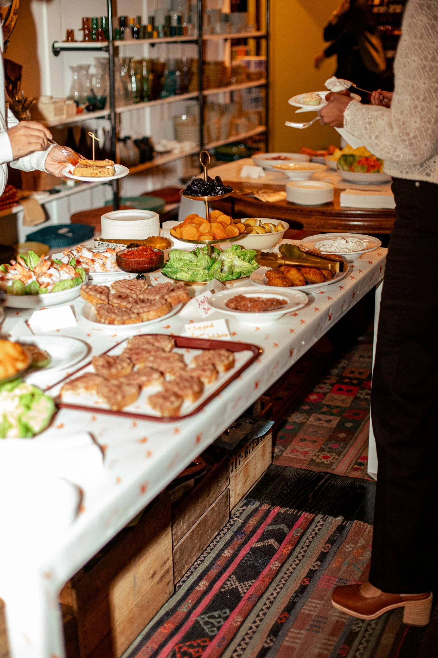 GERTIE buffet table with various dishes including salads, fried foods, and desserts in a cozy indoor setting