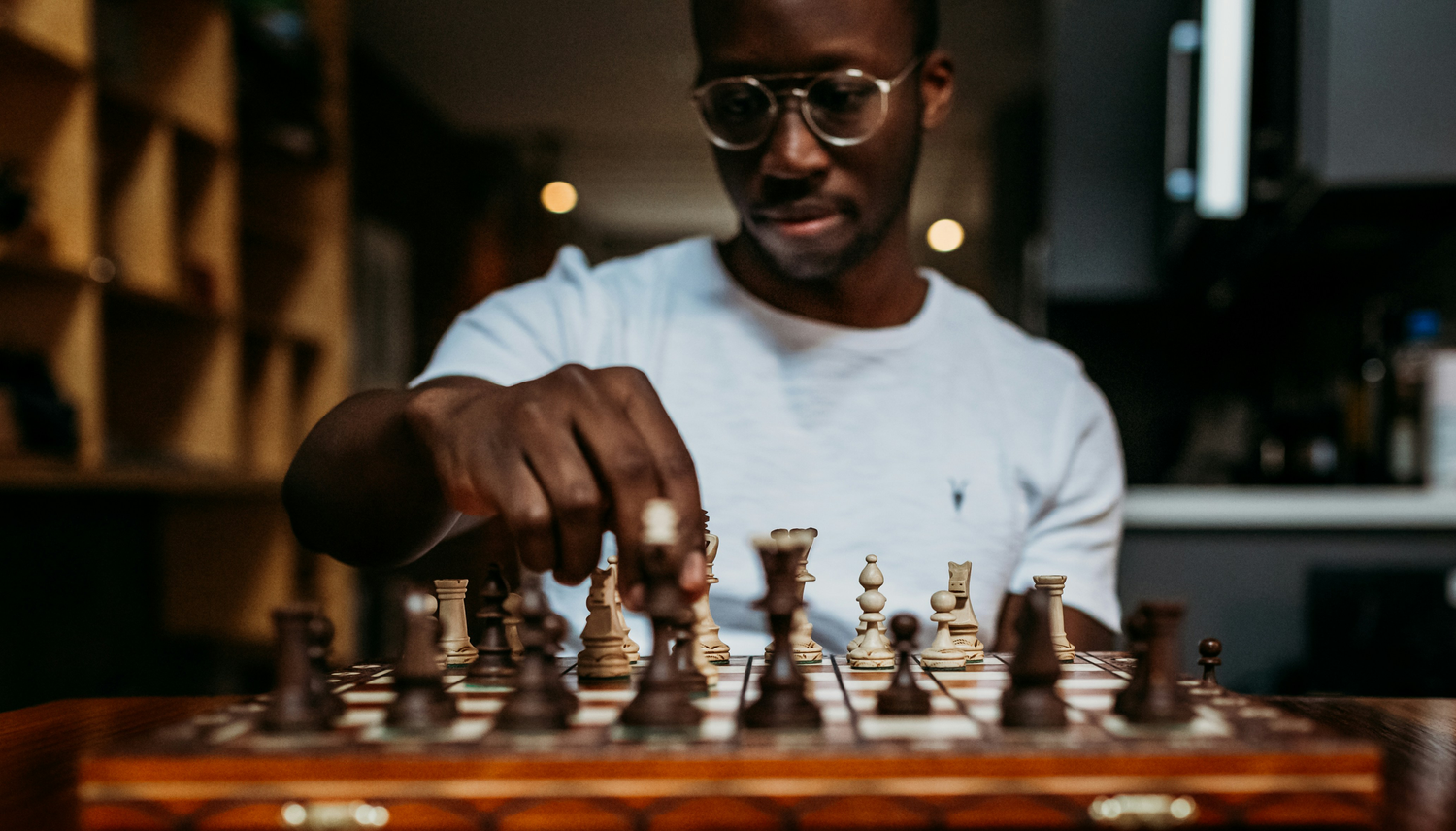 A chess player reaches across the board to make a move.
