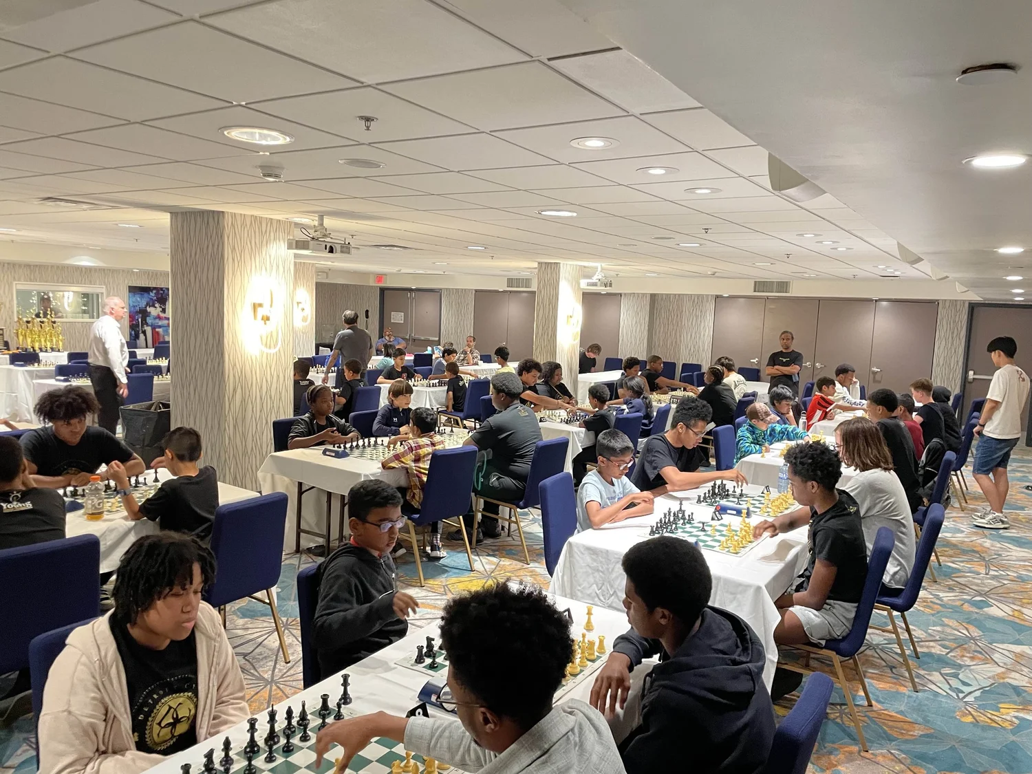 Young chess players competing in a busy Toronto Chess Club tournament hall.