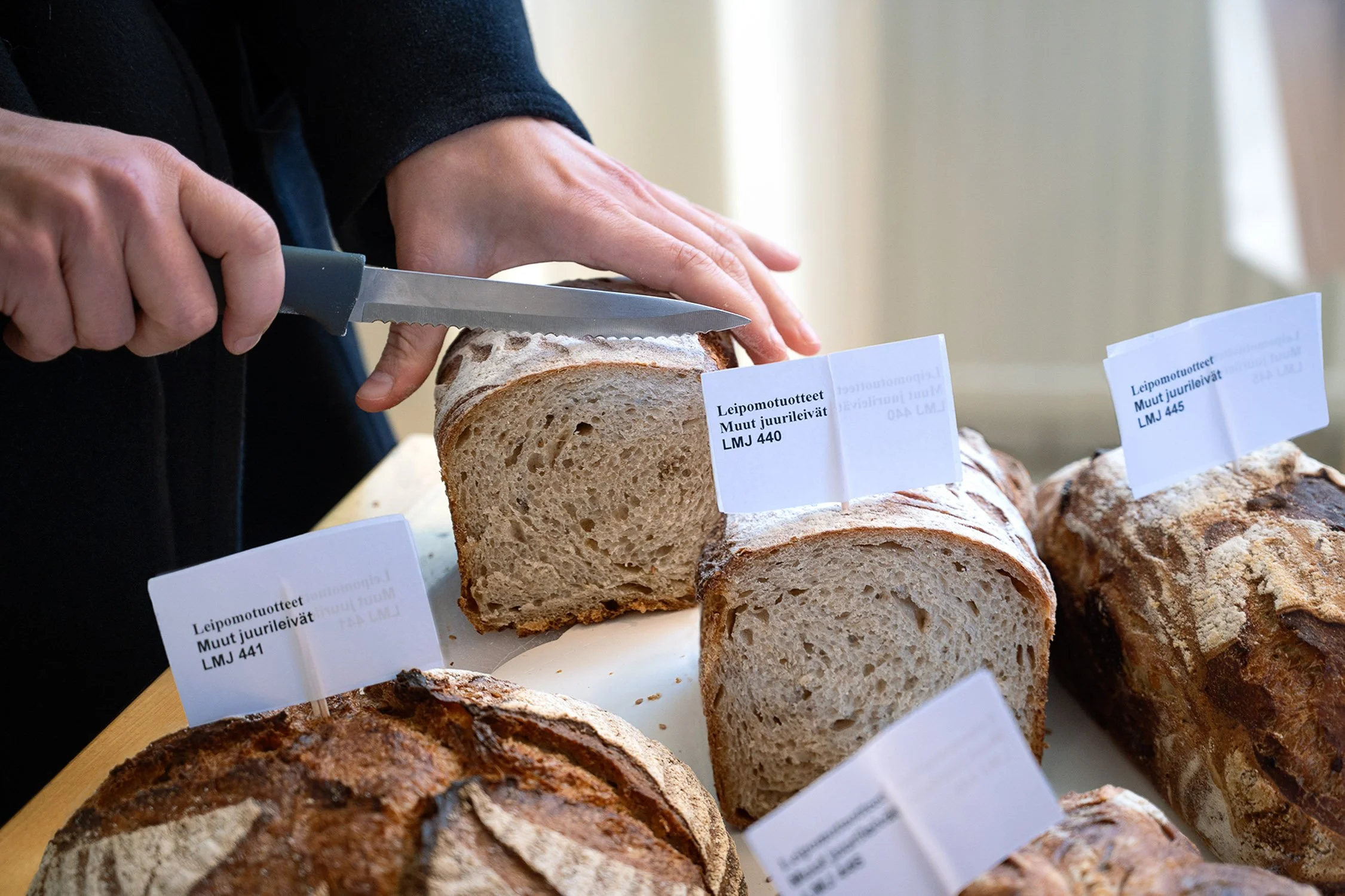 Ihminen leikkaamassa leipää.