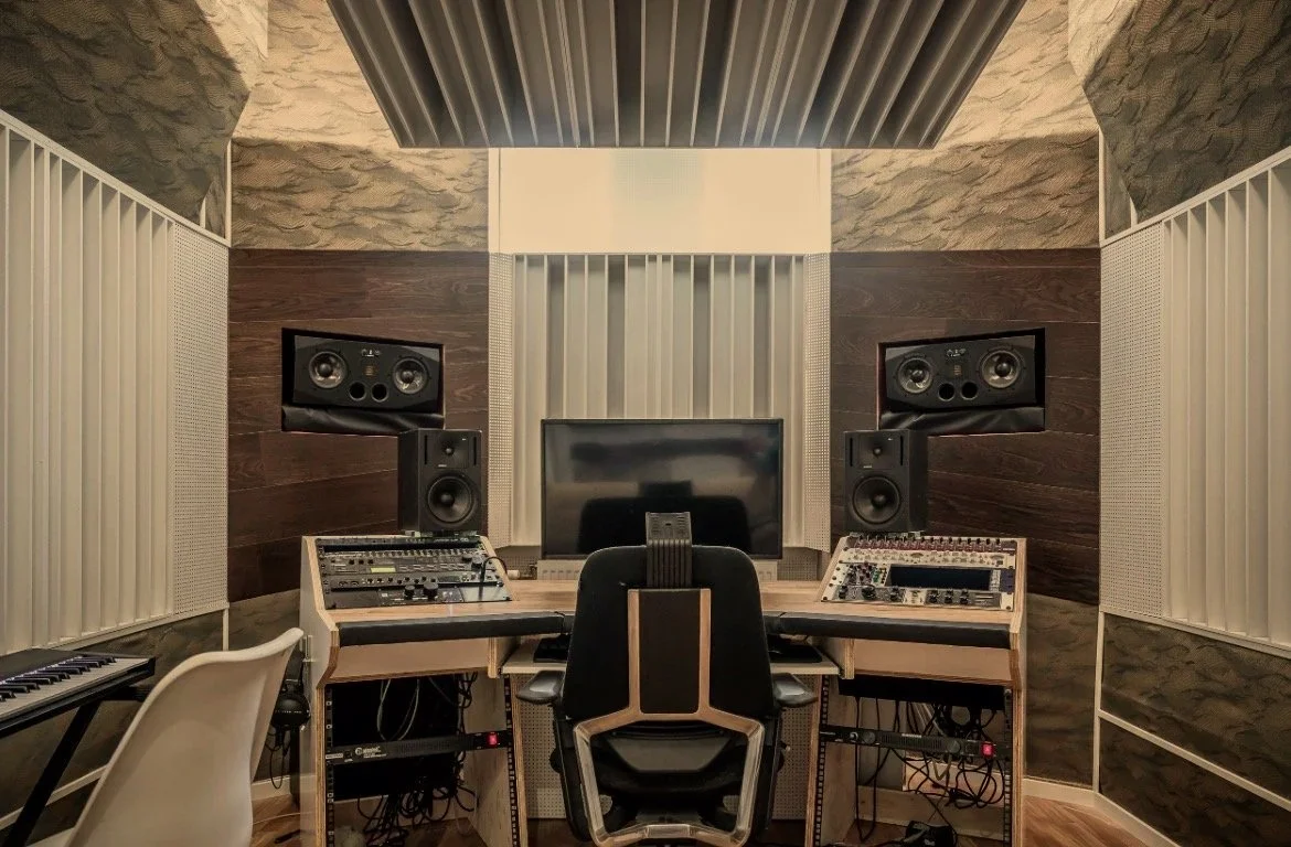 Music production studio with mixing console, two speakers, a monitor, and a keyboard.