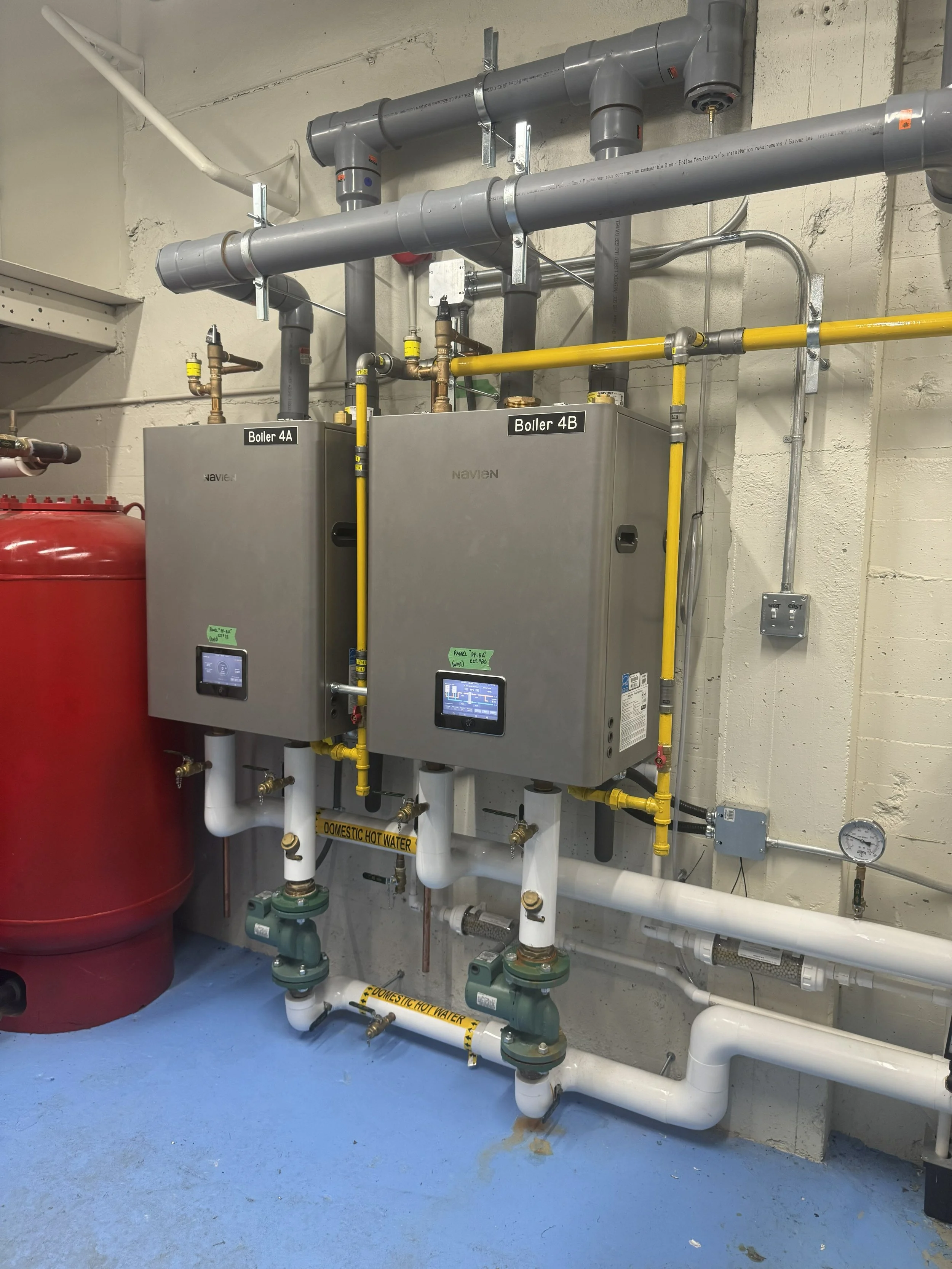 Industrial boiler system with piping, gauges, and control panels, labeled 'Boiler 4A' and 'Boiler 4B', located in a utility room with blue flooring and one large red tank.