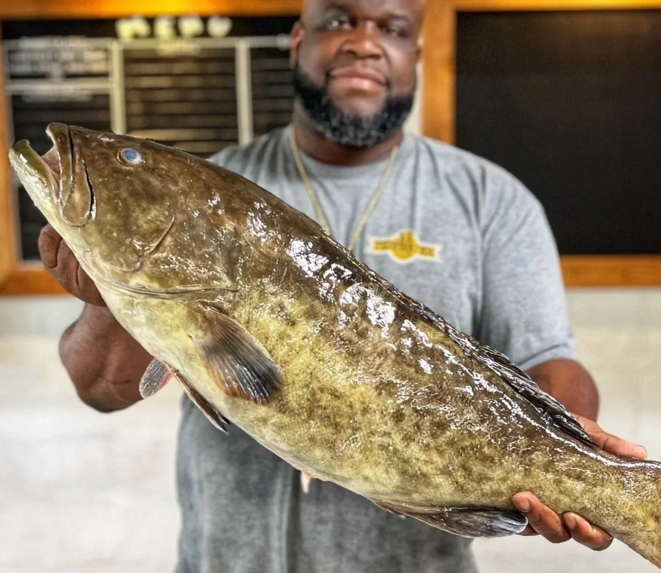 Man holding a large catfish fish indoors.