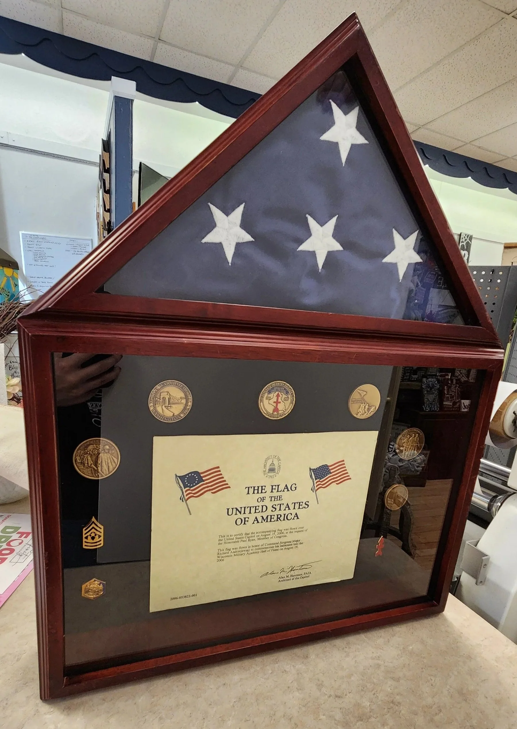 Shadow box with military regalia, such as pins, medals, cards and flag.