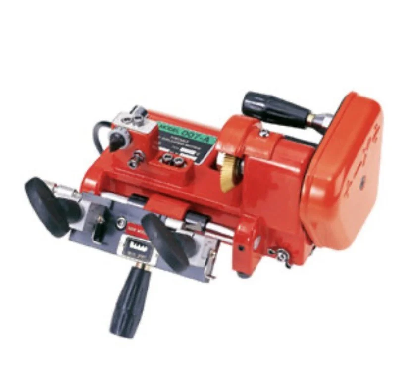 Close-up of a red industrial machine tool or device with various knobs, levers, and attachments.