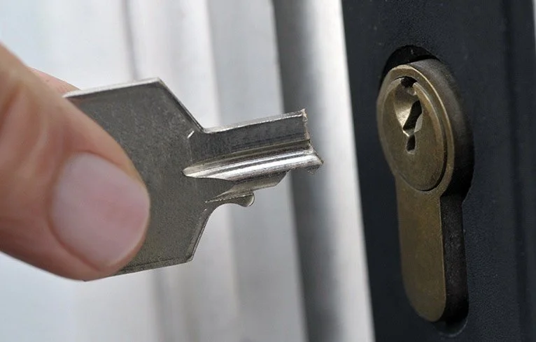 Close-up of a person inserting a key into a lock on a safe or door.