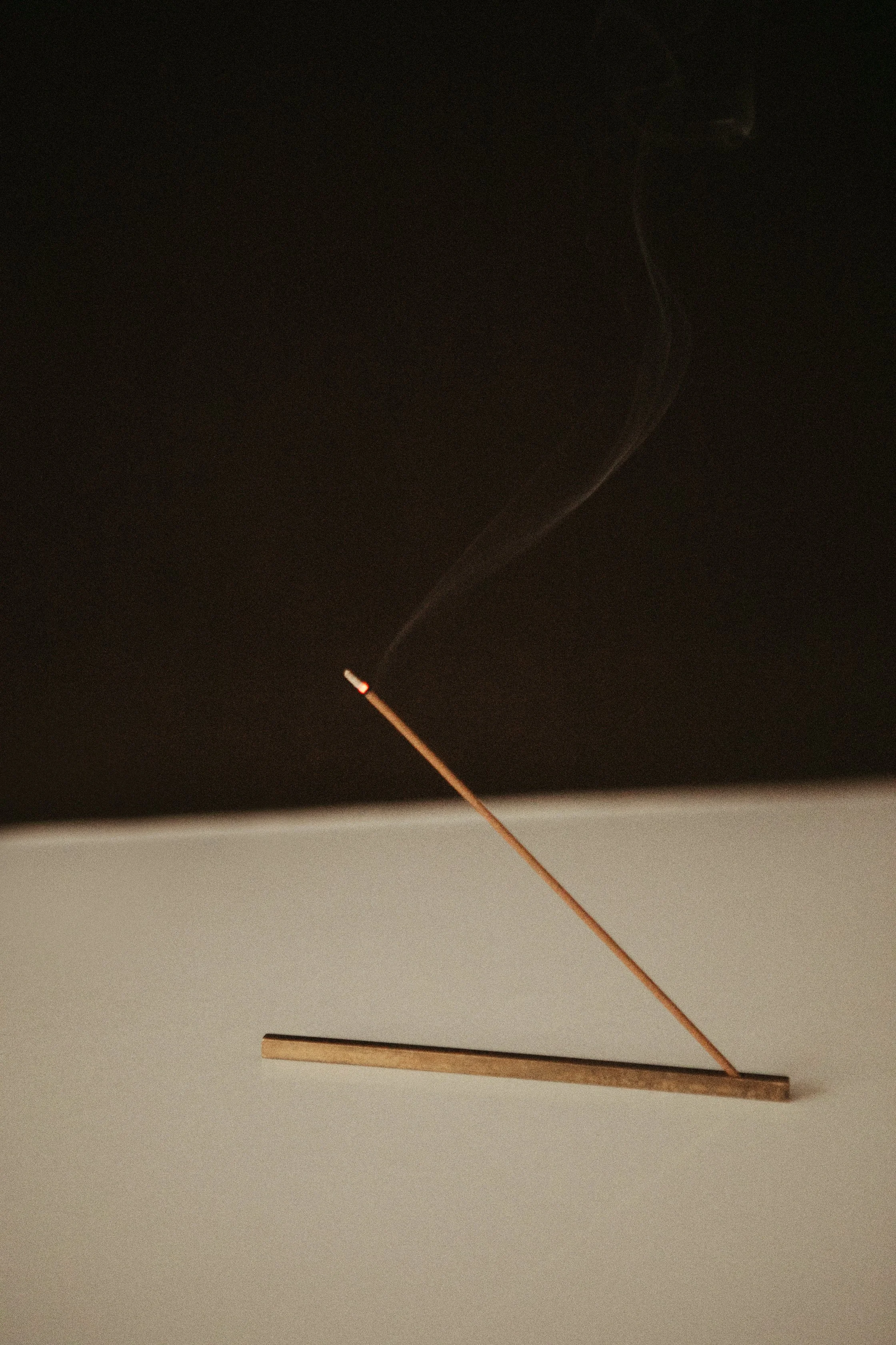 A stick of incense burning on a dark background.