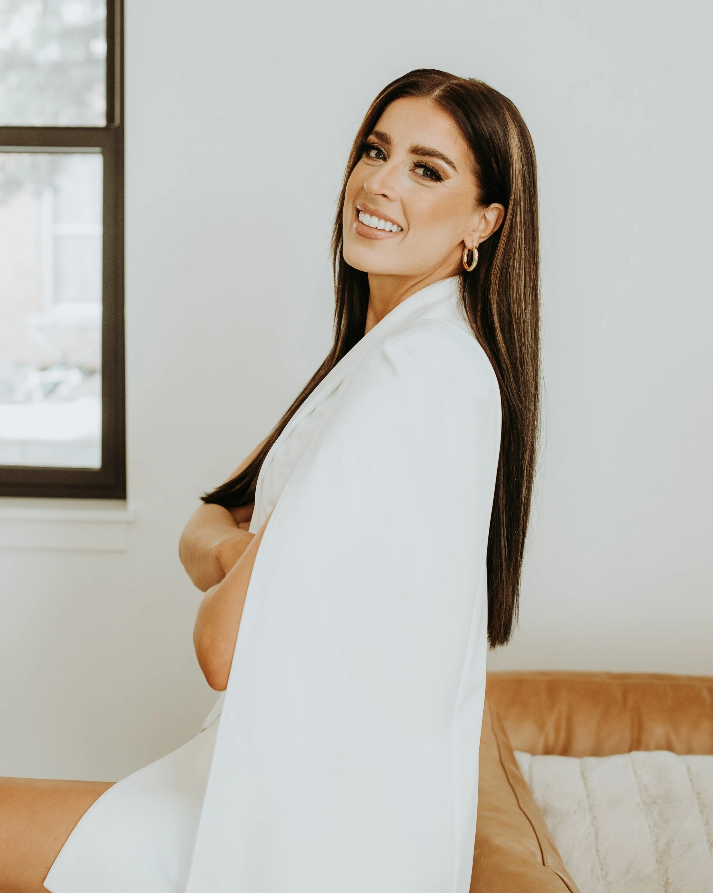 A smiling man with glasses and a beard standing outdoors in an autumn landscape with colorful fall trees in the background.