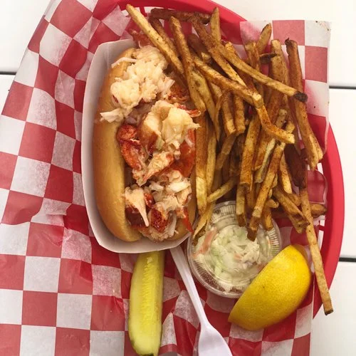 a generous lobster roll with fries, slaw, and lemon