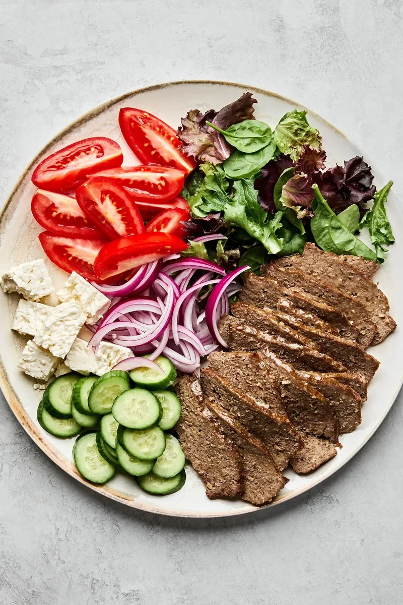 a colorful plate of prepared vegetables and sliced beef