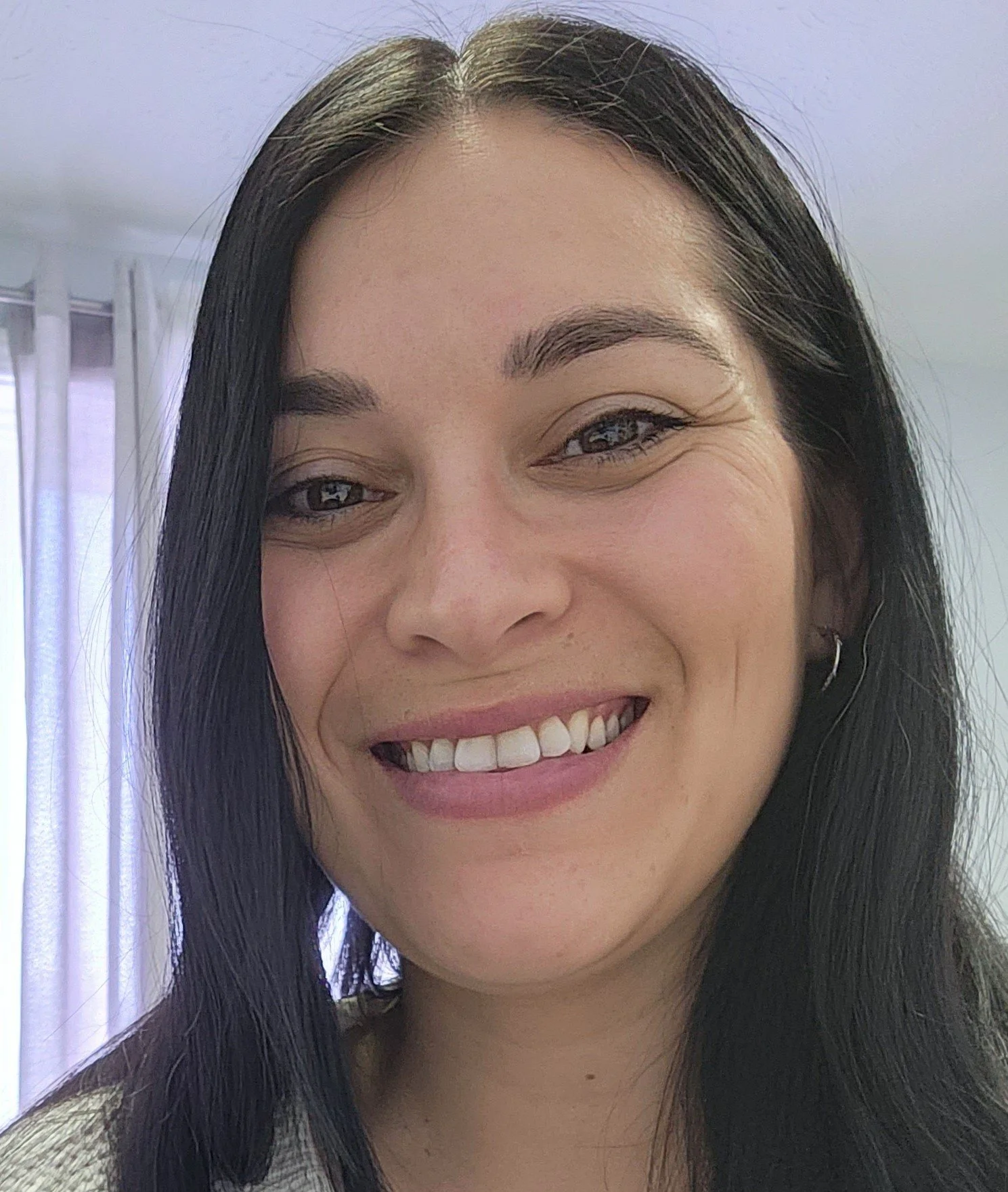 Holly Miller, a smiling woman with long dark hair wearing a striped sweater.