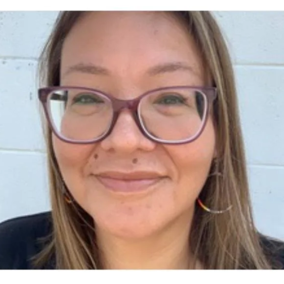 Honarine Scott, a smiling woman with glasses and long hair, wearing beaded earrings.