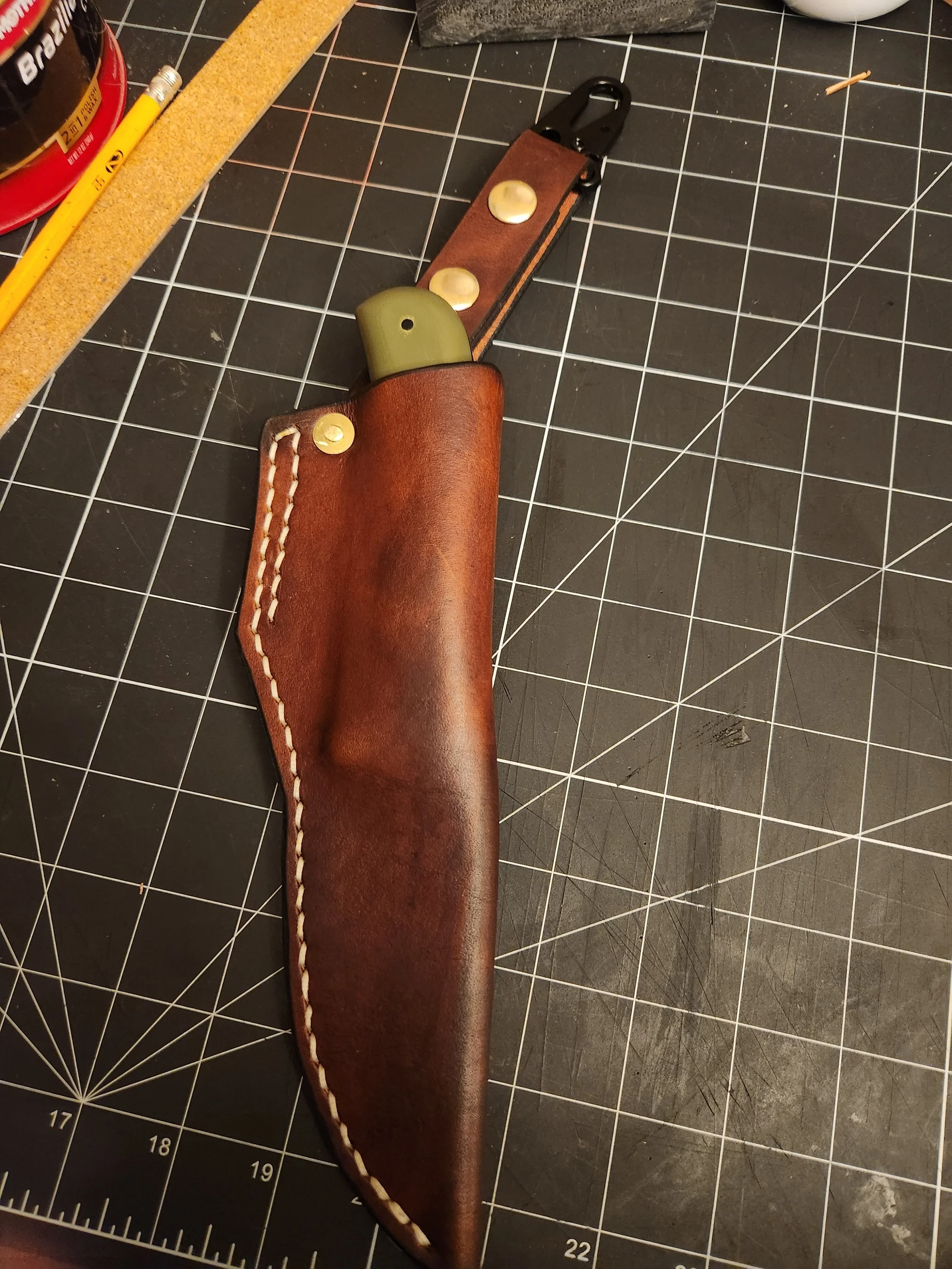 I made this sheath for the knife when I gave it to a friend. Has a D ring with a strap attached. snaps on so you don't need to remove your belt.
