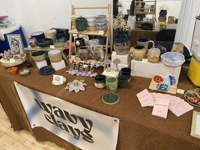 A market table with various pottery pieces for Wavy Clays Ceramics.