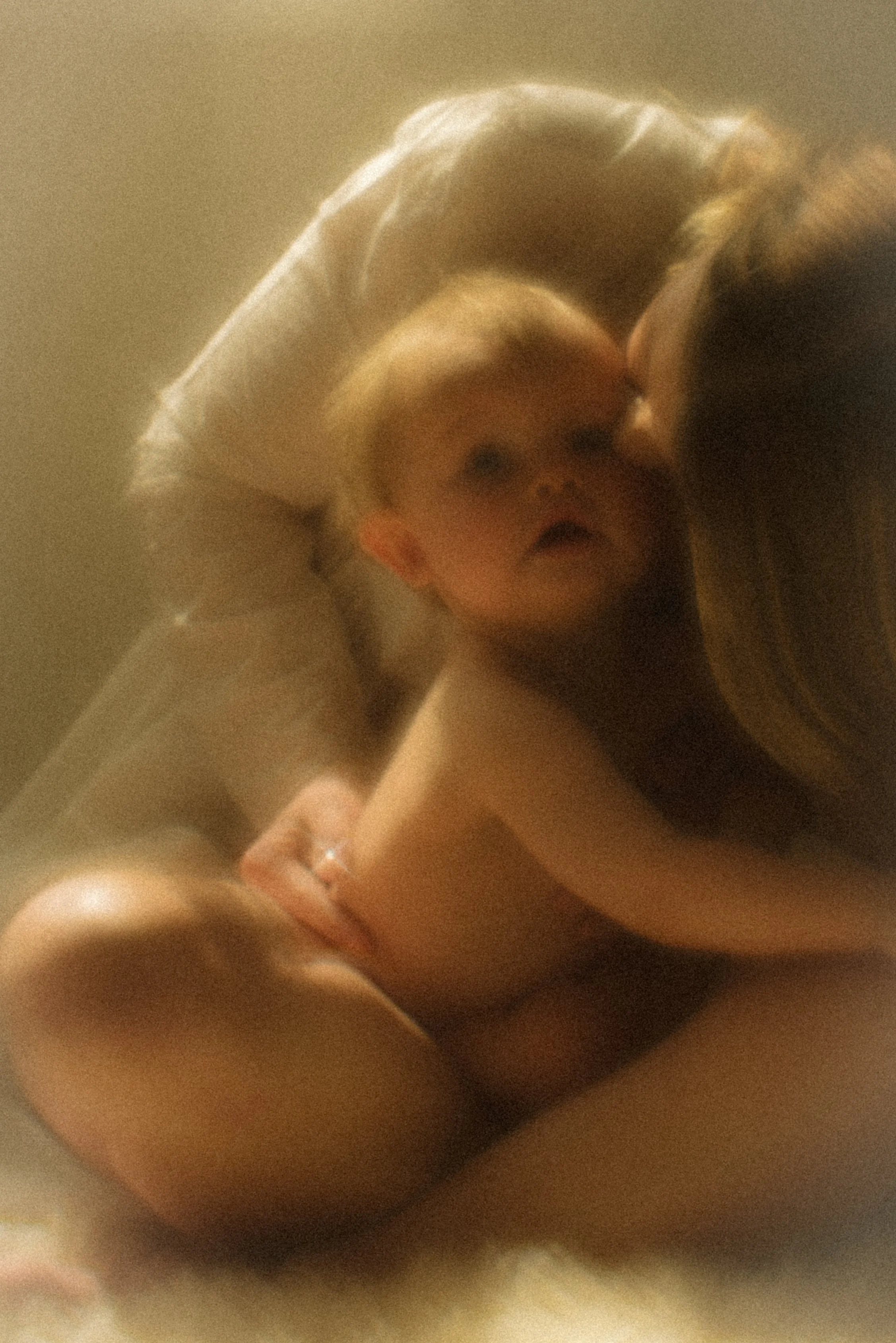 Two women and a child sitting close together, with the woman on the left holding the child and the woman on the right facing them in an intimate moment.