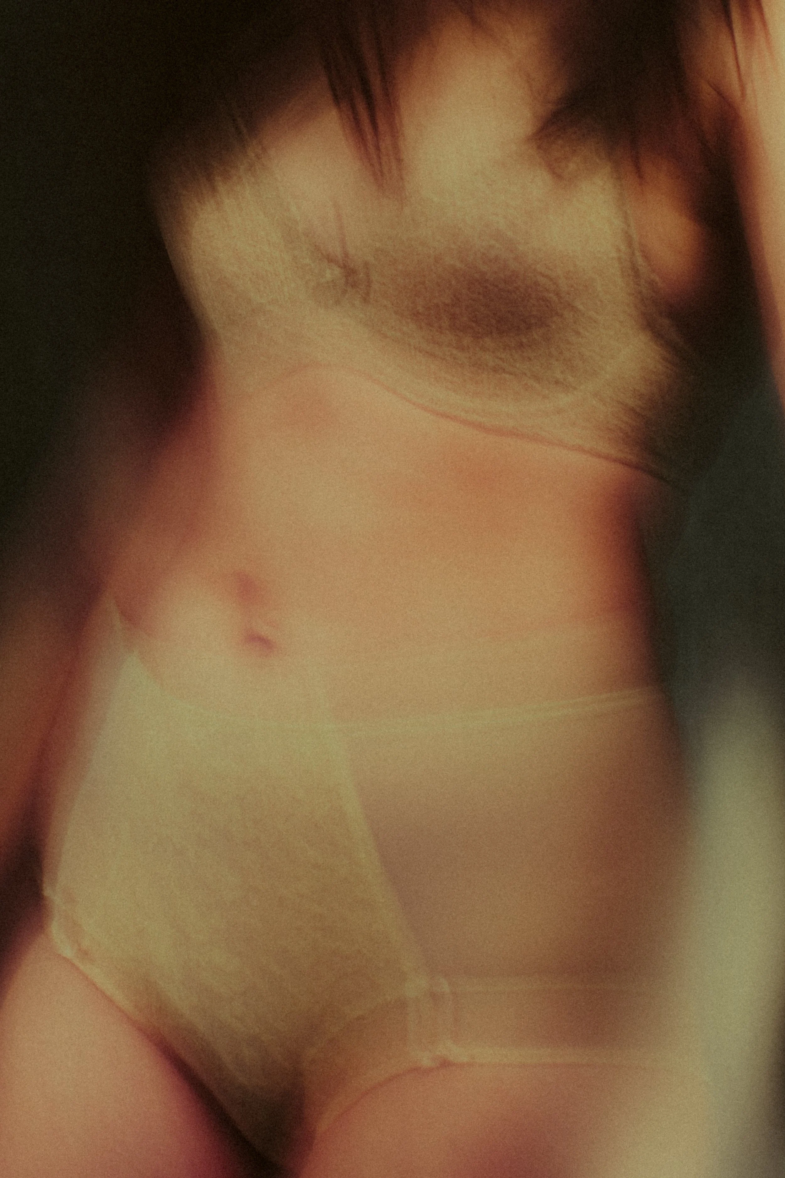 Close-up of a person's midsection wearing beige underwear, showing their stomach and part of their chest.