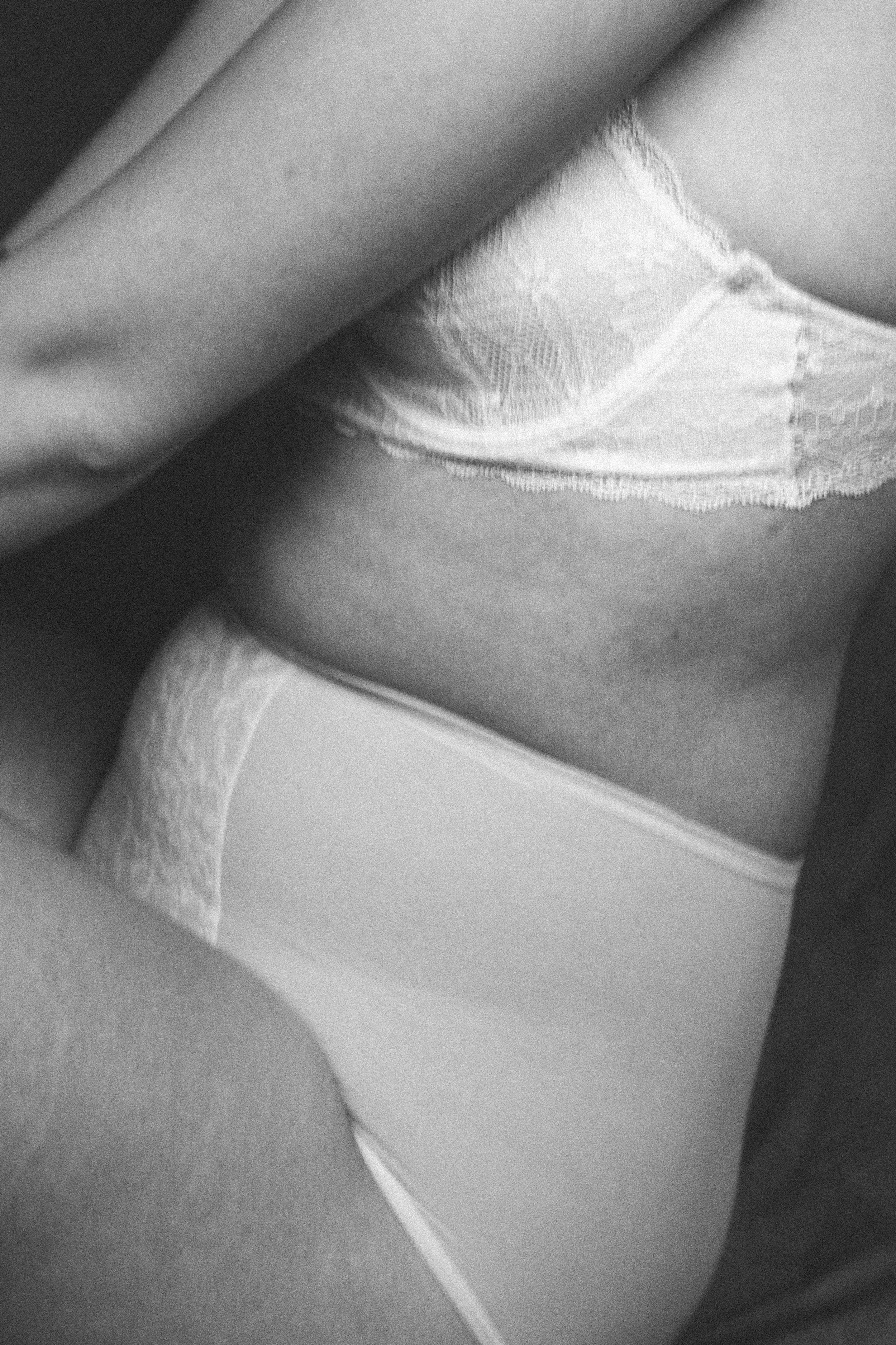 Close-up of a woman wearing lace underwear and a loose top, with her upper body partially covered.