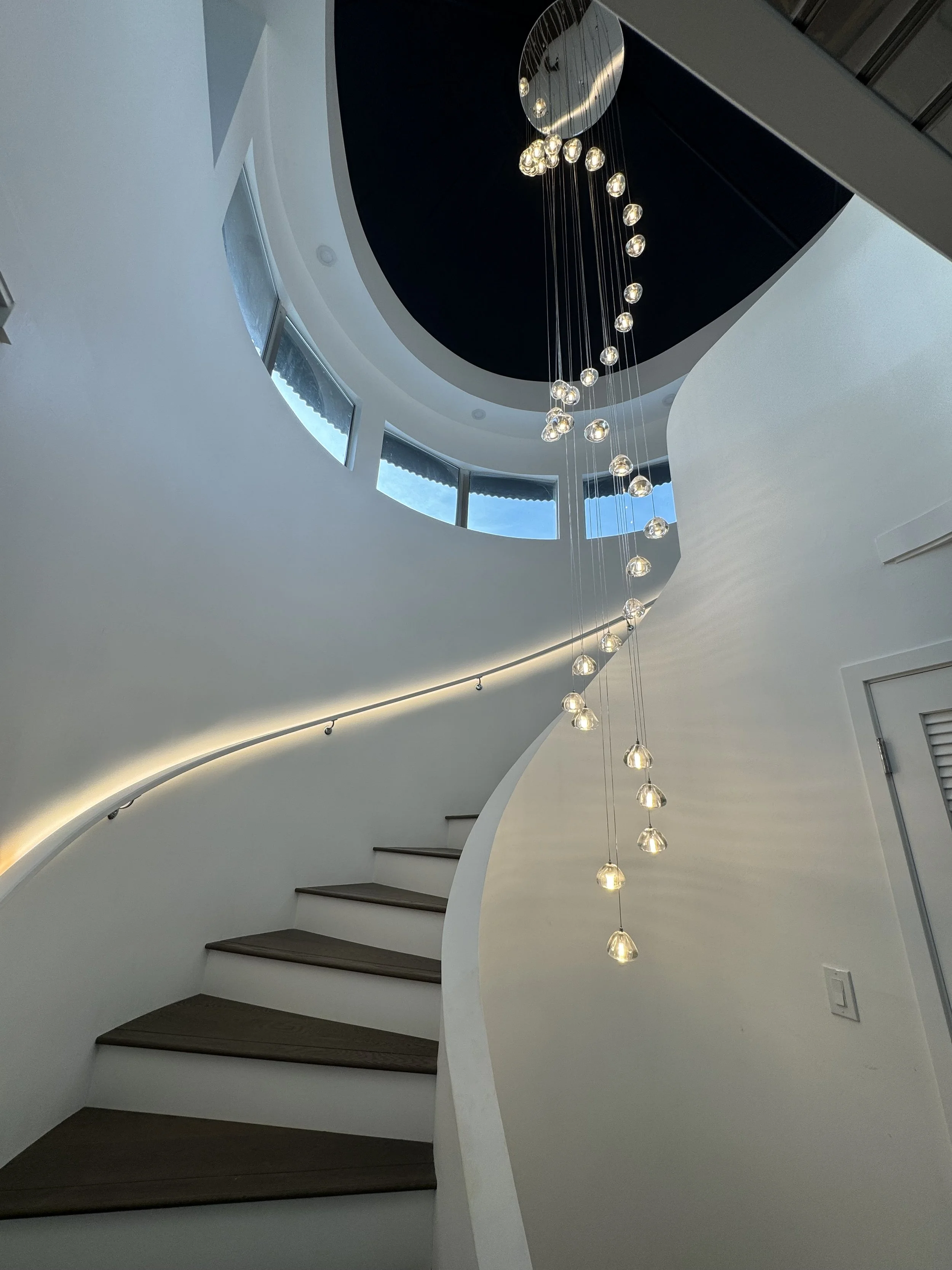 Spiral staircase with wooden steps and modern hanging light fixture inside a contemporary building.