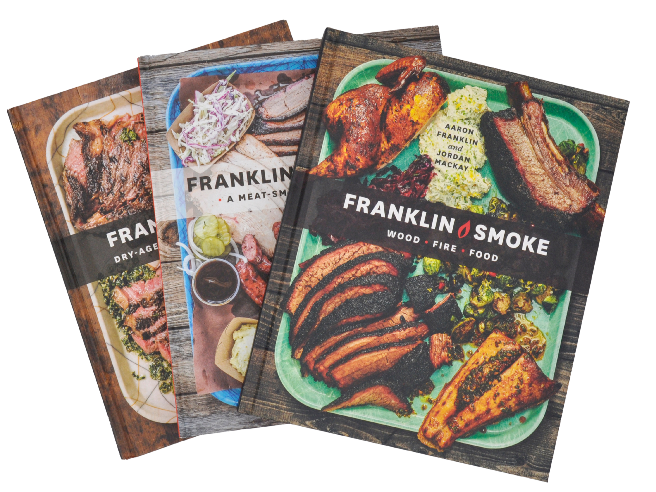 3 books stacks on top of each other and fanned out. Franklin Steak, Franklin Barbecue, and Franklin Smoke.