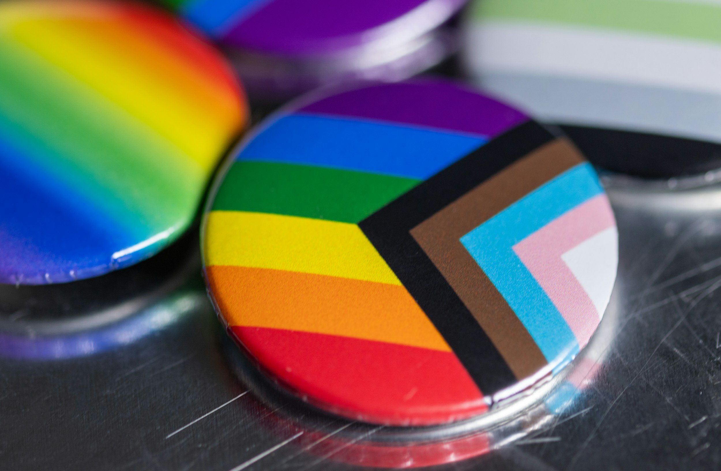 Close-up of a round button with a rainbow-colored chevron pattern and black borders.