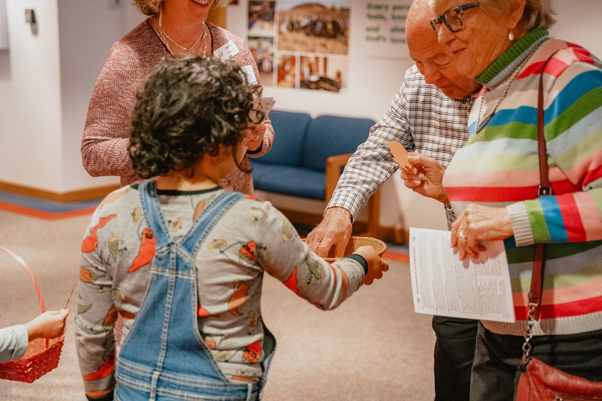 Group of four people, including children and seniors, exchanging cards in a community setting.