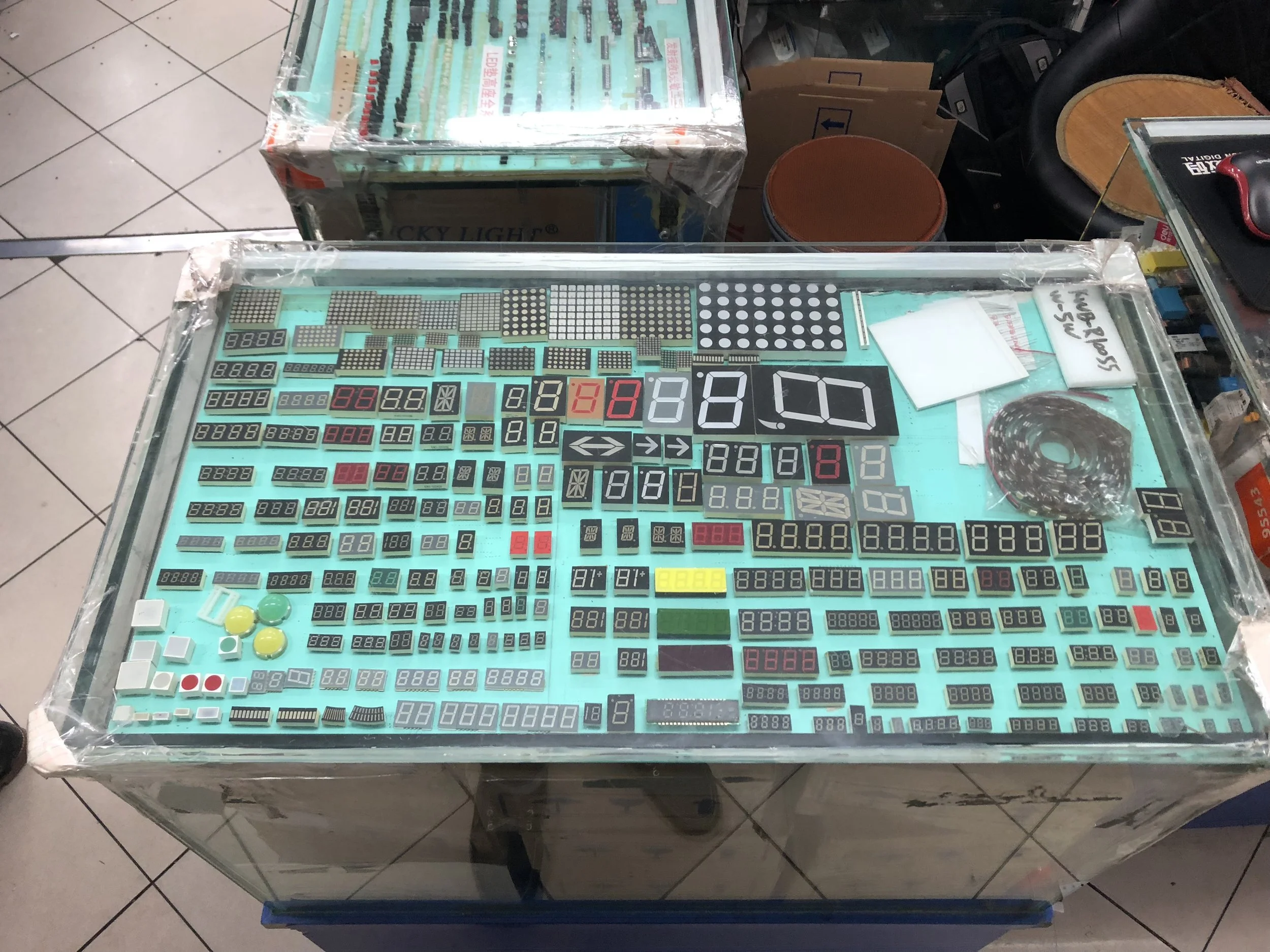 Display table with various electronic digital panels and components covered with clear plastic.