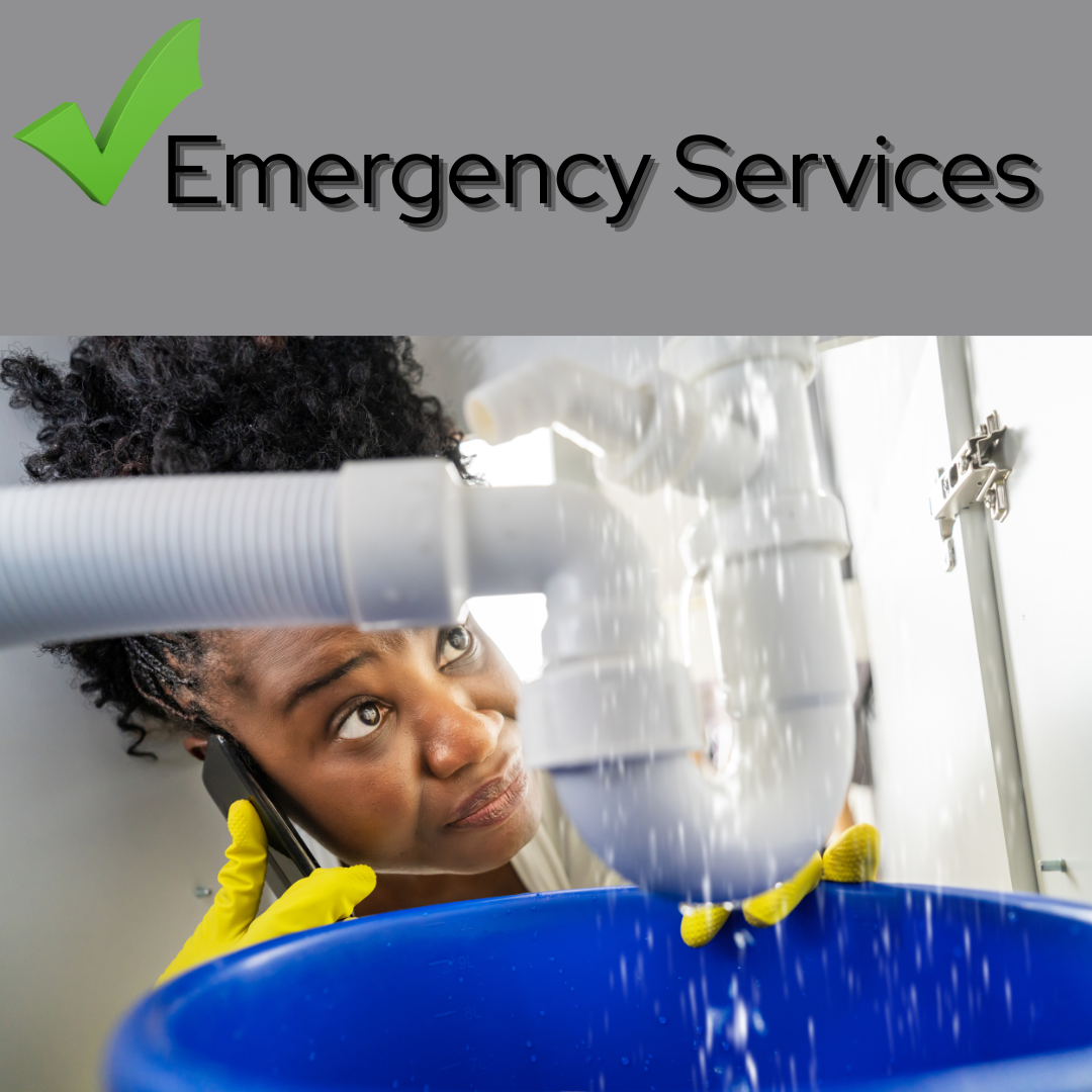 Woman with short curly hair wearing yellow rubber gloves, inspecting a white plumbing pipe system above a blue bucket, while talking on the phone, in a kitchen or utility room.
