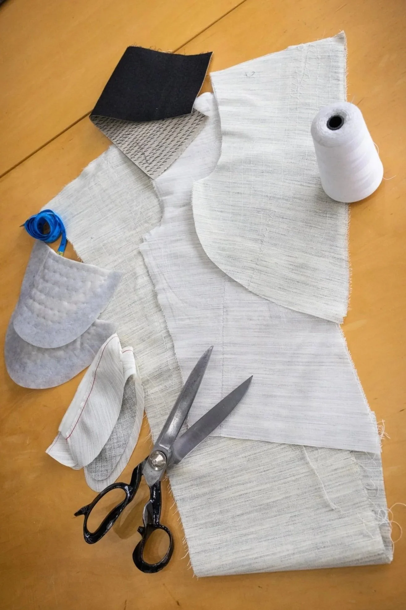 A sewing kit with fabric, scissors, thread, and other sewing supplies on a wooden surface.