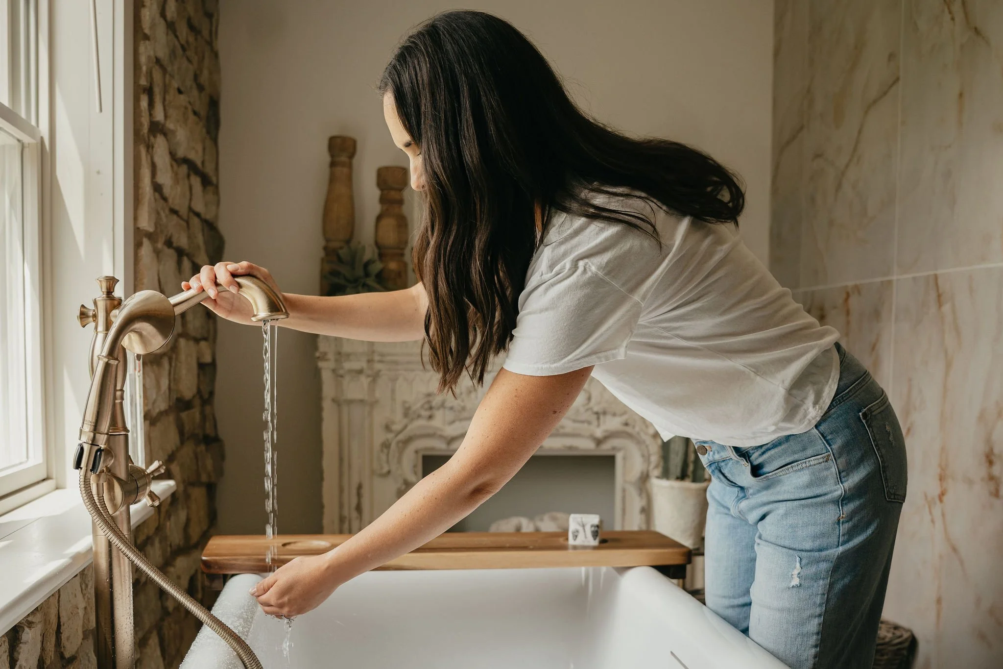 Woman filling a bathtub with water in a bathroom