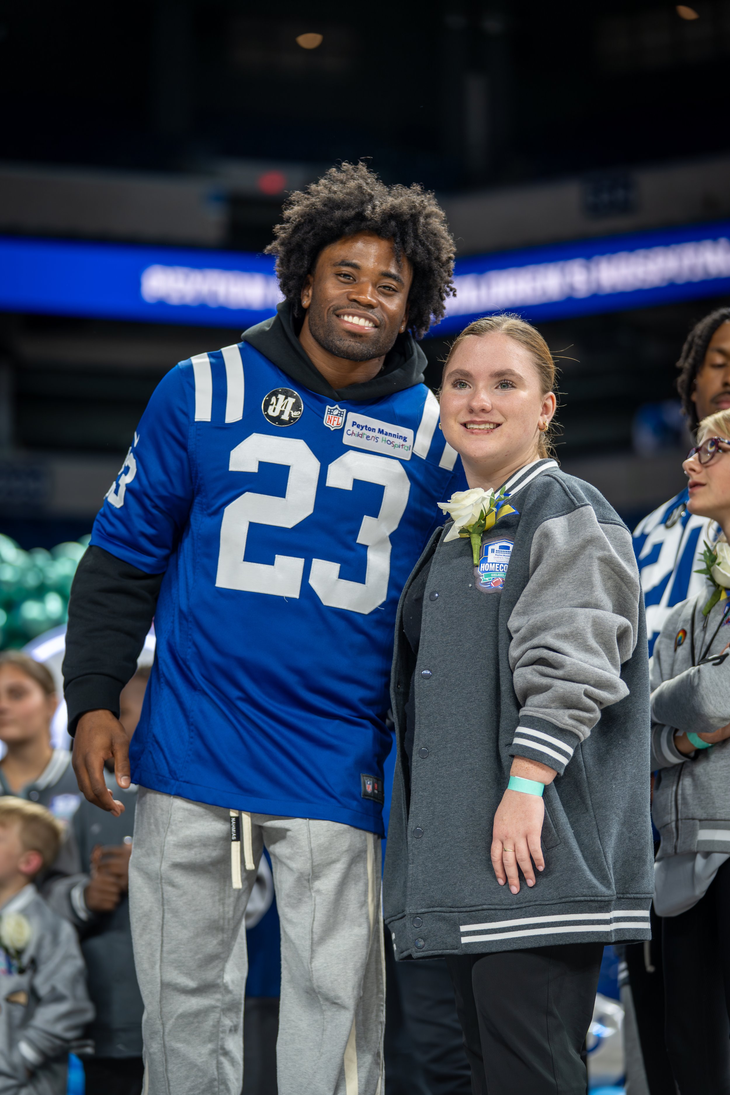 A football player wearing a blue jersey with the number 23 stands next to a woman in a gray jacket, both smiling at an event. Indianapolis Colts
