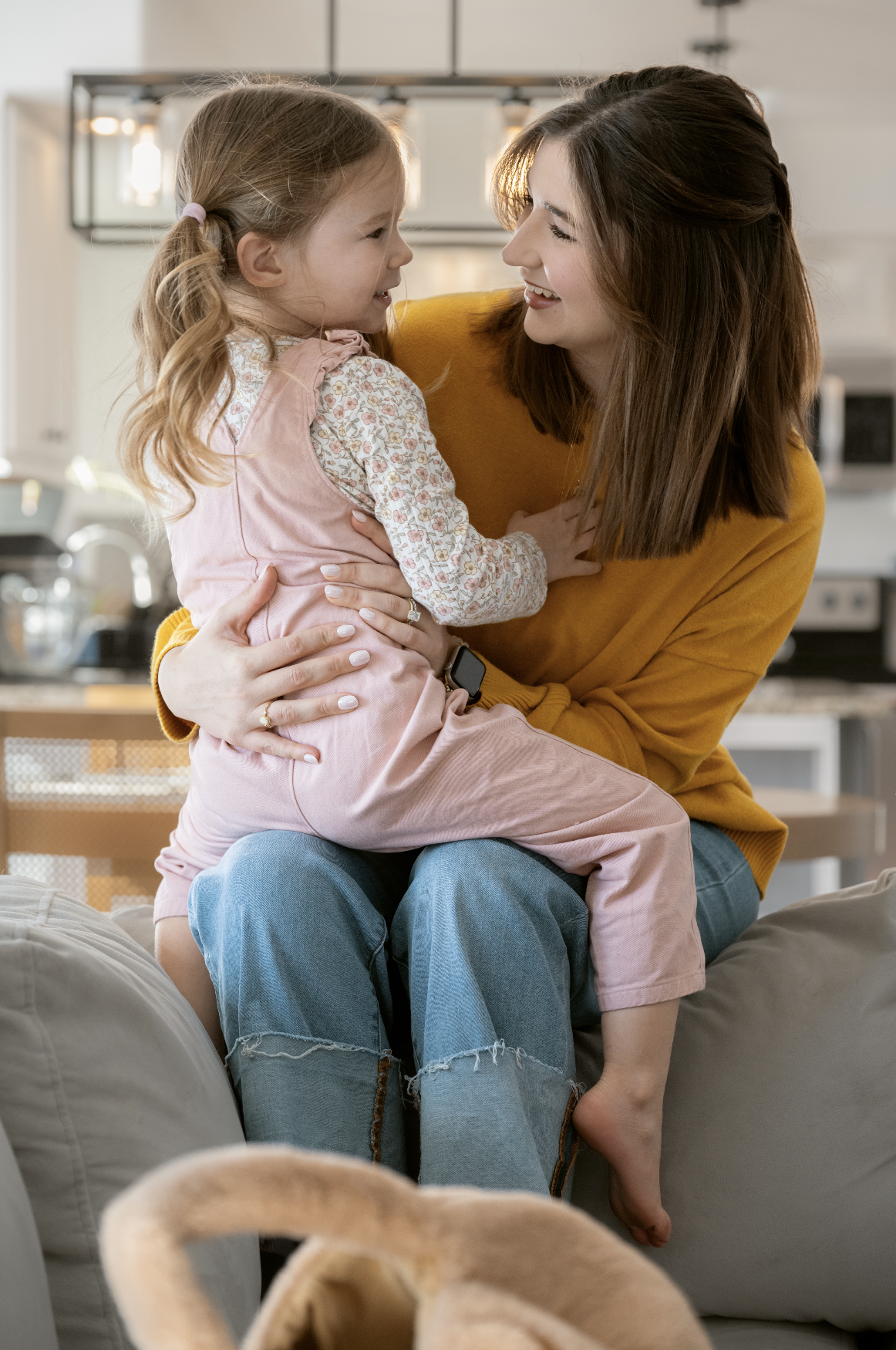 Work-from-home mom sitting with her young daughter at home