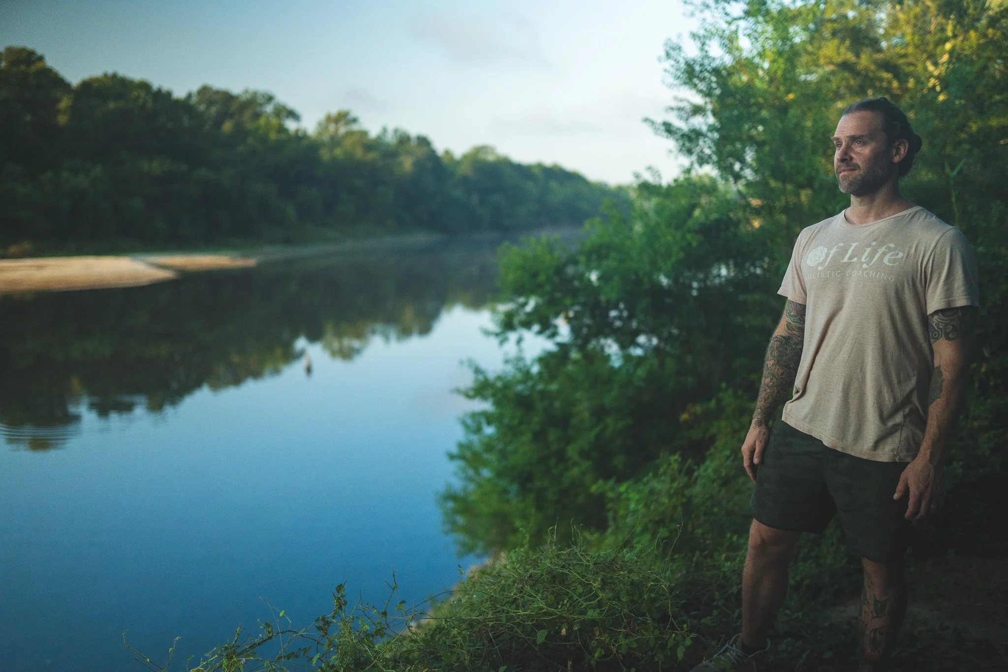 Holistic coach reflecting outdoors near water, representing mental clarity and wellness